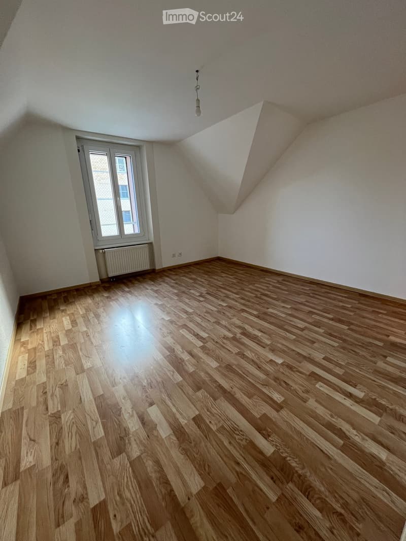 an empty room with wooden floor, radiator, glass window, white walls and ceiling, view of outside building