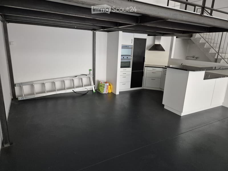 Empty kitchen with white cabinets, black countertops, and a black floor. No furniture or appliances are present.