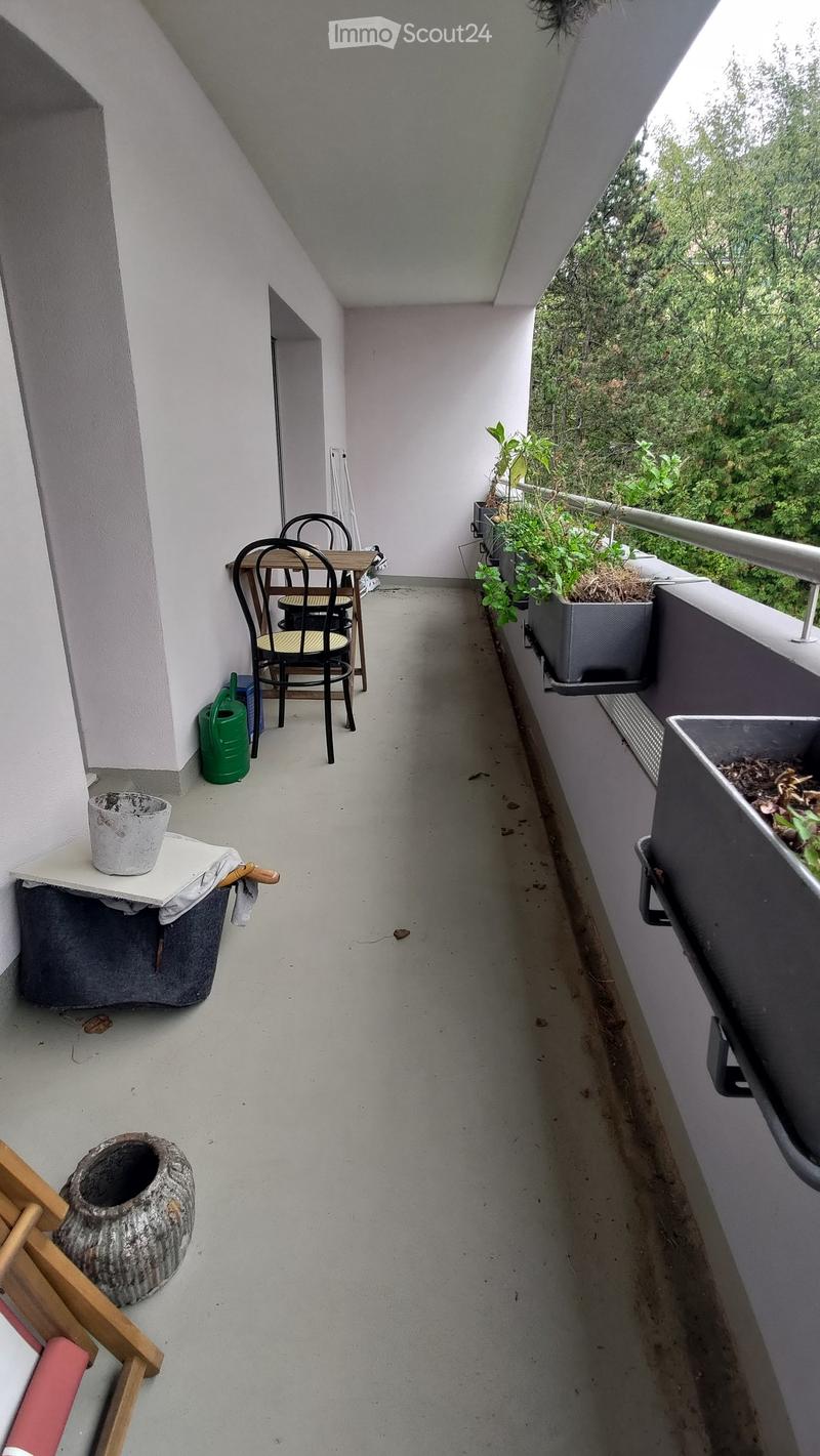 Balcony with a small table and chairs, potted plants, and a garden pot on the floor.