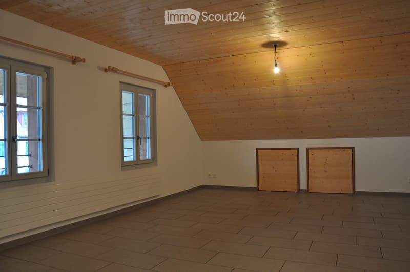 Empty room with wooden ceiling, tiled floor, and two windows. No furniture or equipment present.