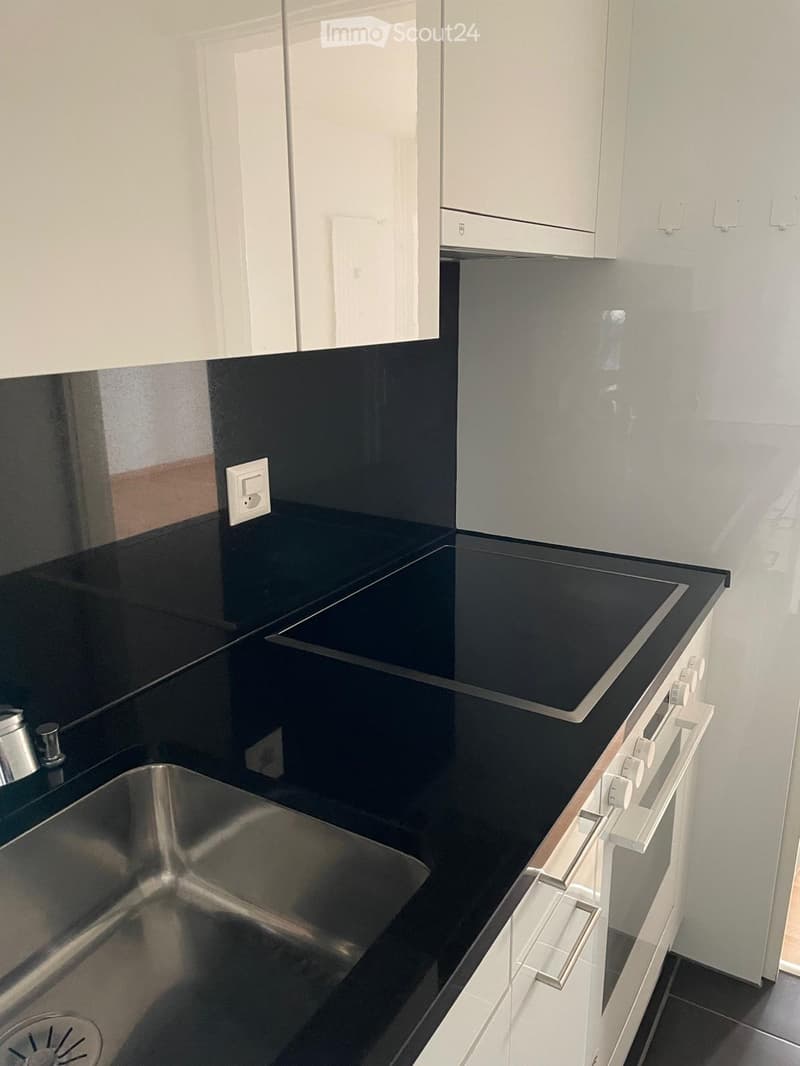 Modern kitchen with black countertops, stainless steel sink, and built-in stove.