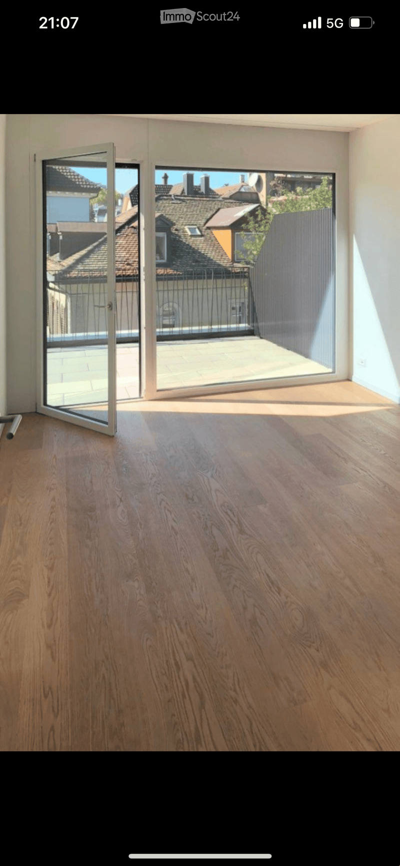 Empty room with wooden flooring and large sliding glass doors leading to a balcony or terrace area.