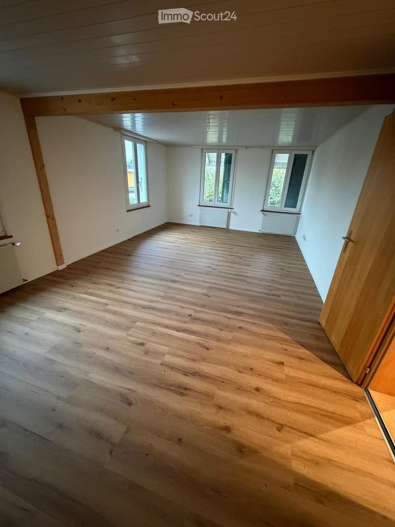 Empty room with wooden flooring, white walls, and multiple windows allowing natural light. No furniture or equipment present.