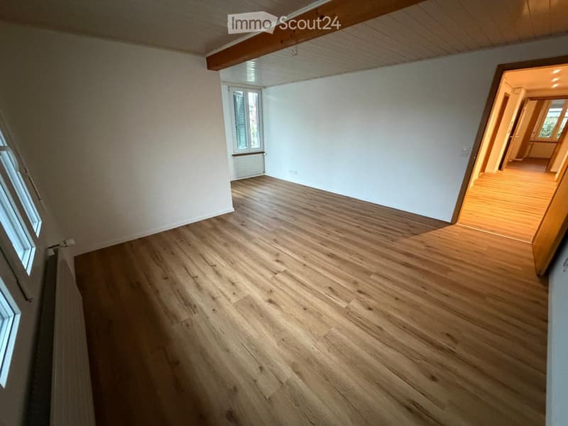 Empty room with wooden flooring, white walls, and large windows. No furniture or equipment present.