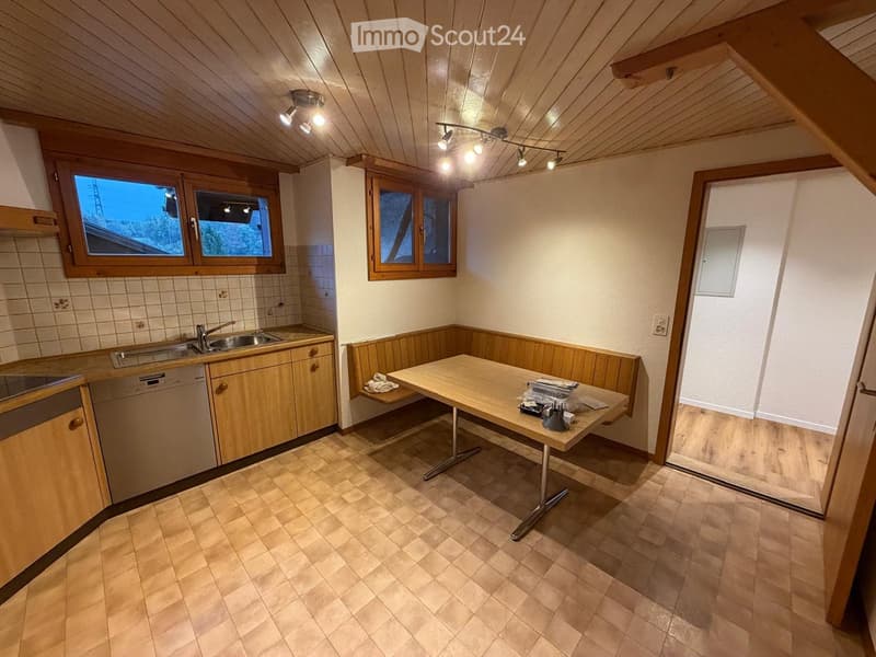 Cozy kitchen with wooden cabinets, a sink, dishwasher, and a small dining table with a bench seating area.
