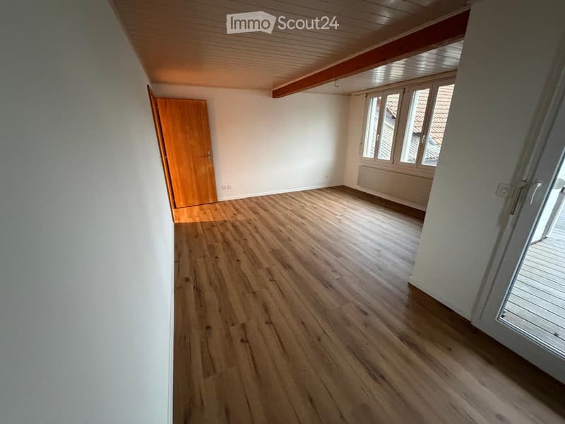 Empty room with wooden flooring, white walls, and large windows. No furniture or equipment is present.
