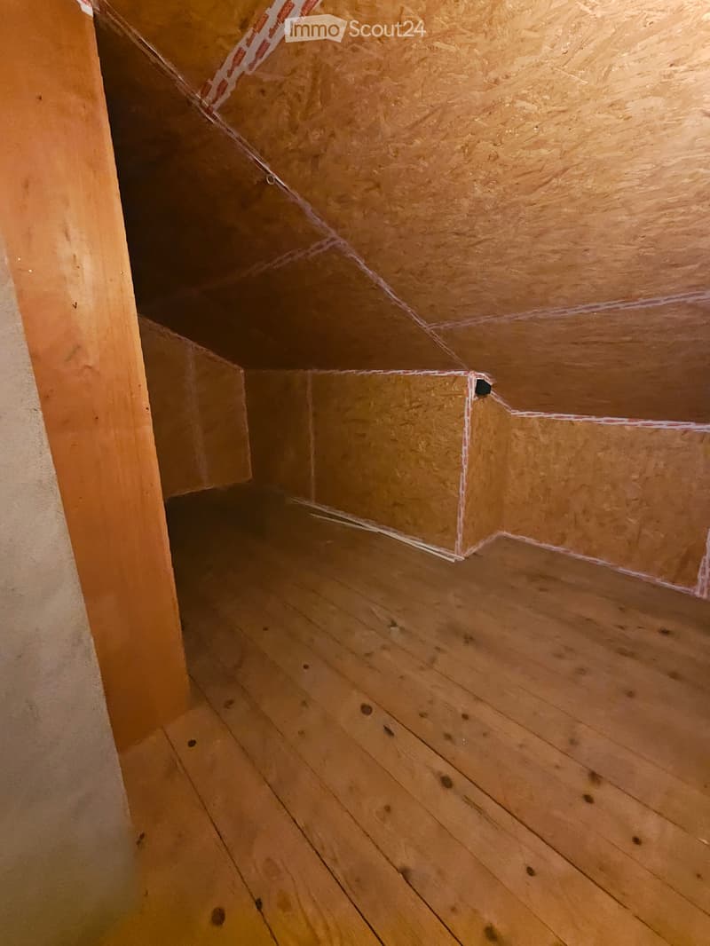 Empty attic space with wooden floor and exposed wooden ceiling beams, no furniture or equipment.