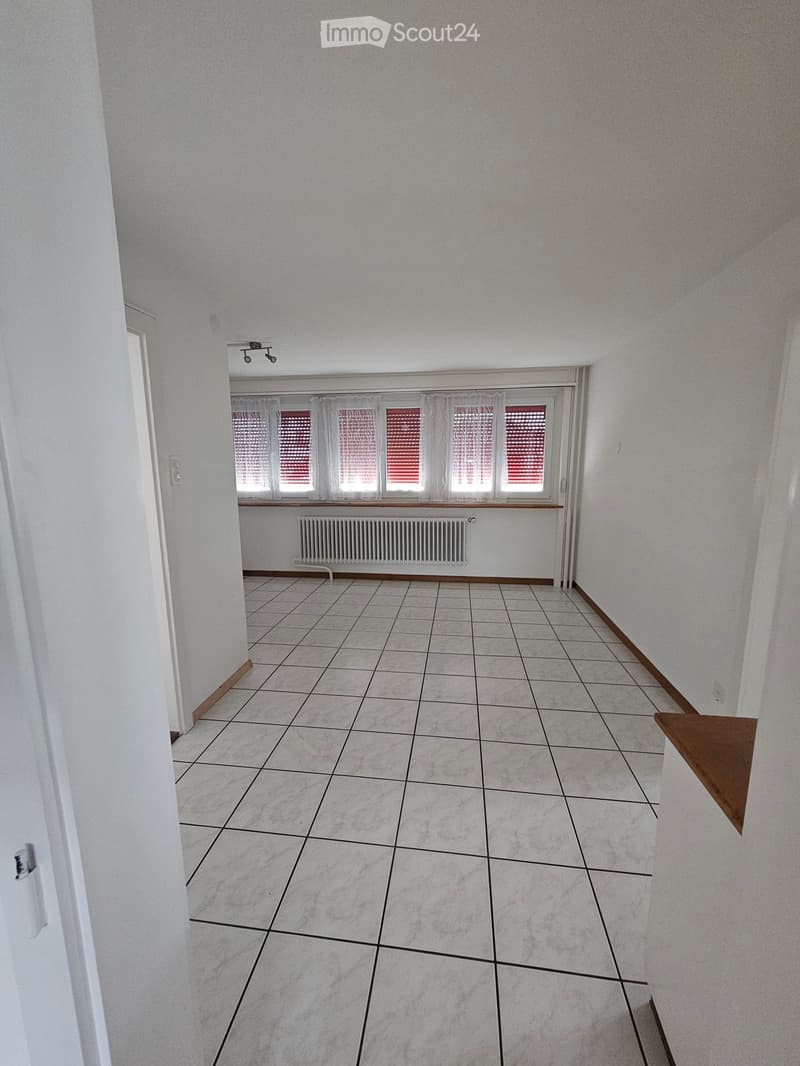 Empty room with tiled floor, white walls, and large windows with blinds. No furniture or equipment present.