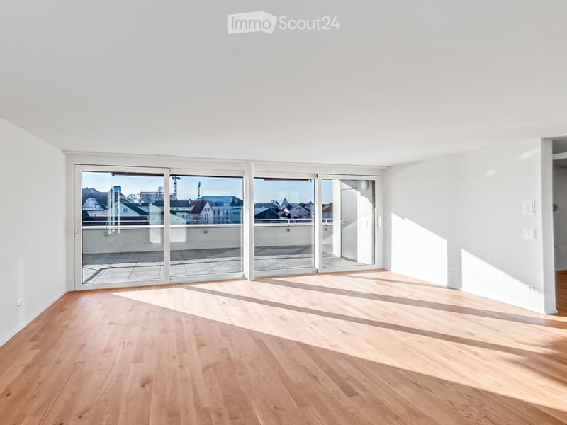 Empty room with light wooden flooring and large glass sliding doors leading to a balcony.