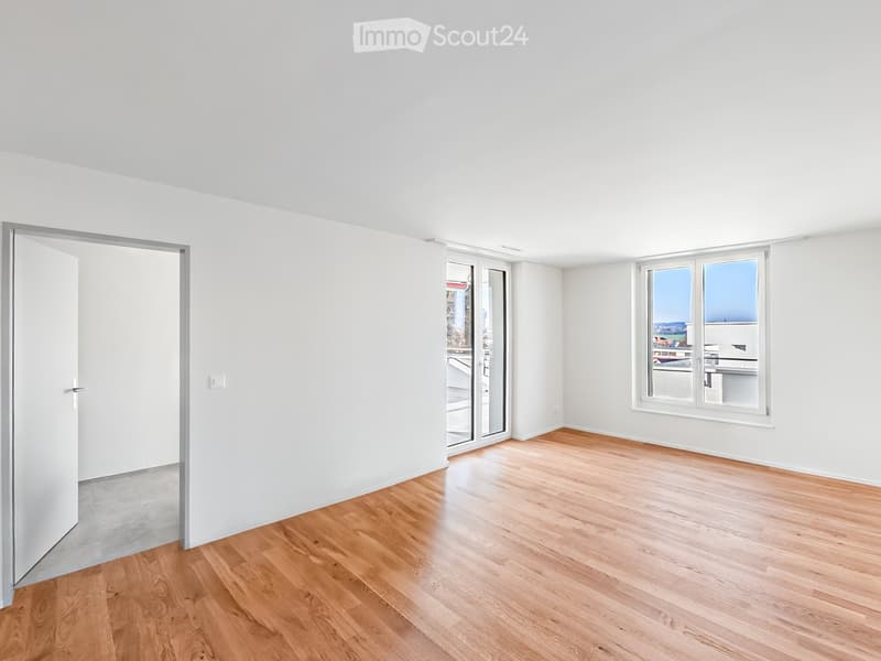 Empty room with white walls, wooden flooring, and large windows. No furniture or equipment present.