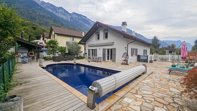 Outdoor area with a swimming pool, wooden decking, lounge chairs, and a view of mountains.