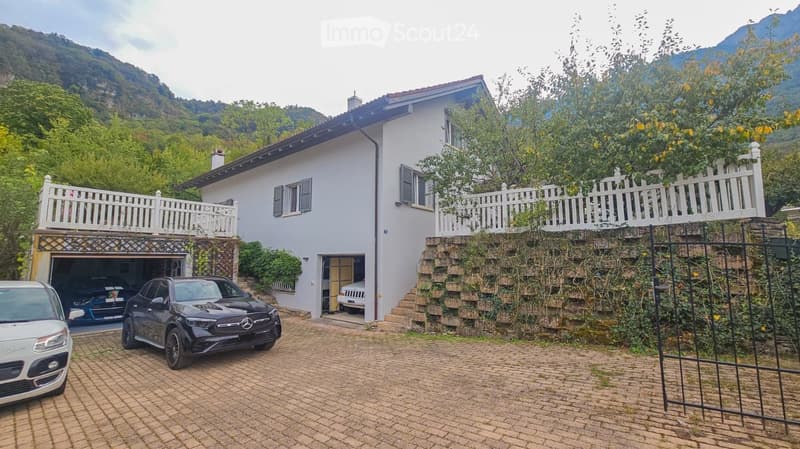 Two-story white house with a garage, balconies, and a scenic mountain view in the background.