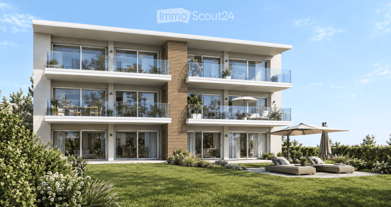 Modern two-story house with large glass windows, balconies, and outdoor seating area with lounge chairs and umbrellas.