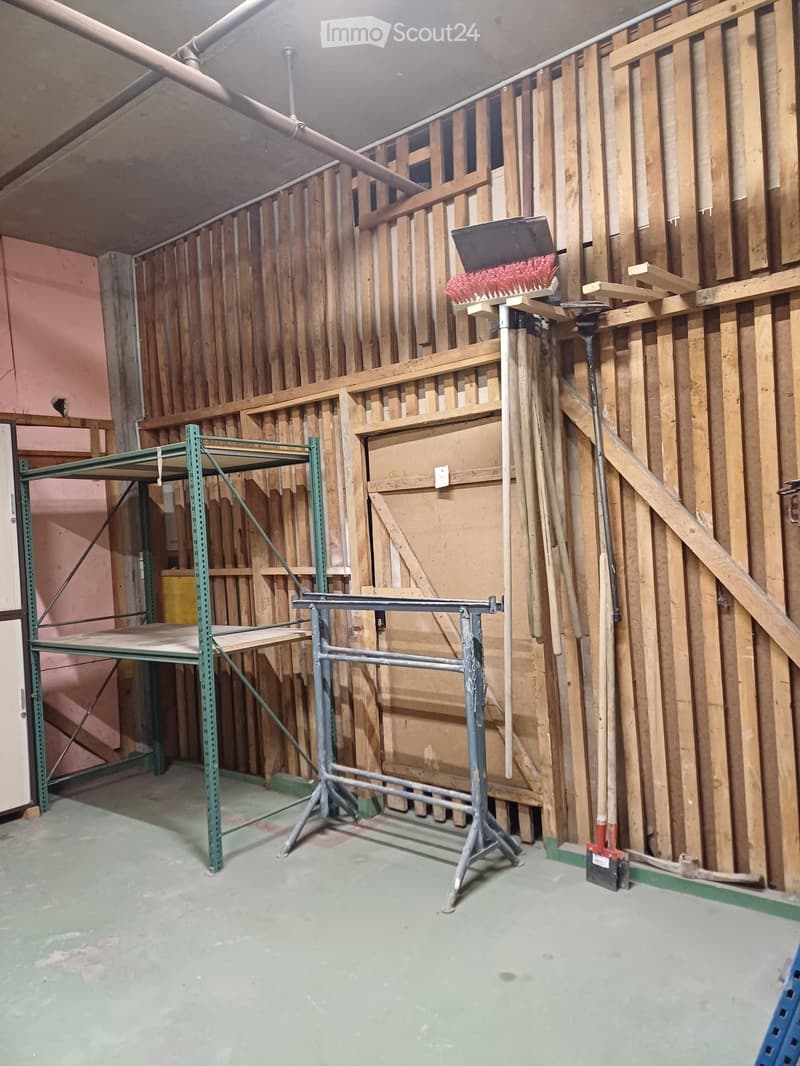 Empty room with exposed wooden framing, metal scaffolding, and construction tools, including a ladder and a brush on a stand.