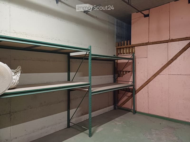 Empty room with metal shelving unit, concrete floor, and exposed brick wall.