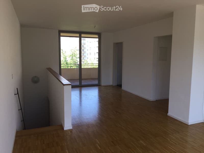Empty room with wooden flooring, white walls, and a sliding glass door leading to a balcony.