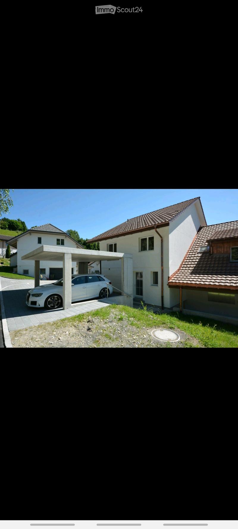 Modern two-story house with a tiled roof, white exterior, and a covered garage area with a parked car.