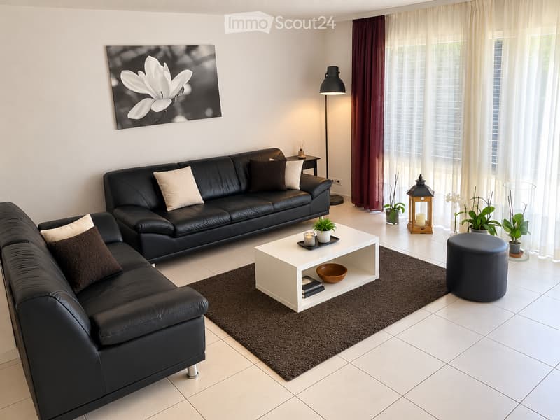 Modern living room with black leather sofa, white coffee table, floor lamp, and decorative items.