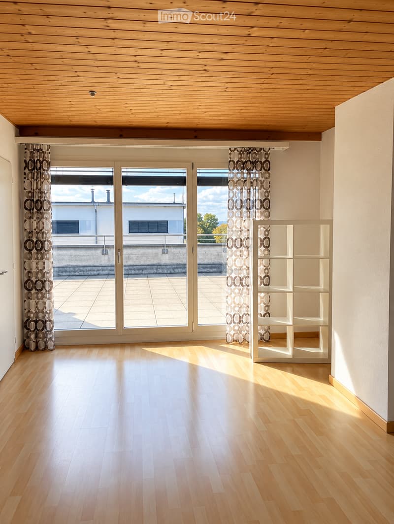 Empty room with light wooden flooring, white walls, large sliding glass doors leading to a balcony, and a white shelving unit in the corner.
