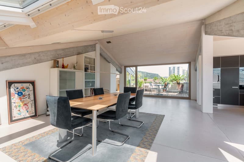 Modern dining area with a wooden dining table, six chairs, a cabinet with glass doors, and a picture frame on the wall. The space features a skylight and large windows offering a view of the outdoor area.