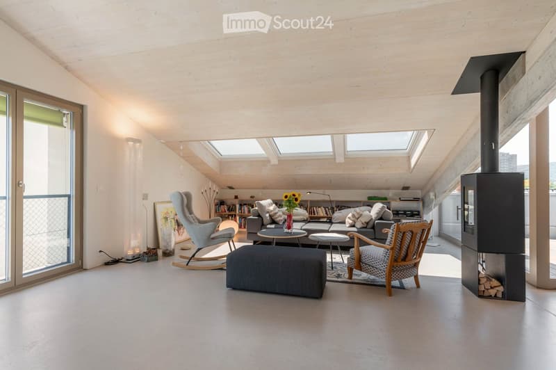 Modern living room with skylights, fireplace, grey sofa, coffee table, ottoman, rocking chair, wooden chair, bookshelf, and vase with sunflowers.