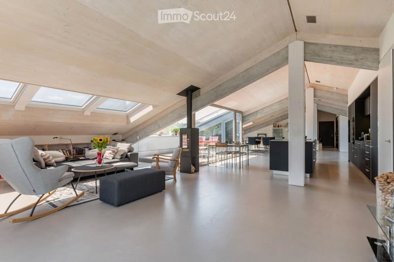 Modern living room with exposed wooden ceiling, large windows, and skylights. Features a grey sofa, coffee table, bench, armchair, fireplace, dining area with table and chairs, and a kitchen island.