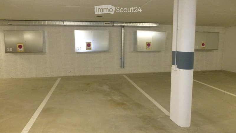 Underground parking area with numbered private parking spaces, marked lines, and a central support column.