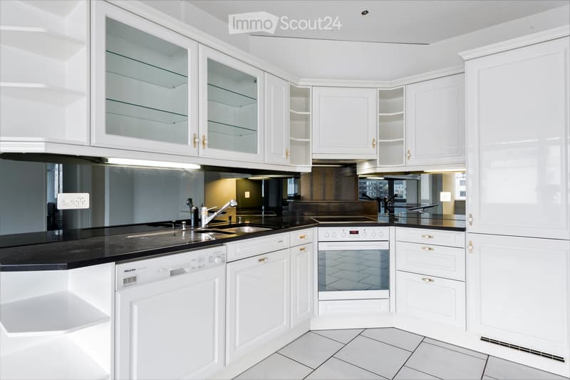 Modern kitchen with white cabinets, black countertops, stainless steel sink, oven, and dishwasher.