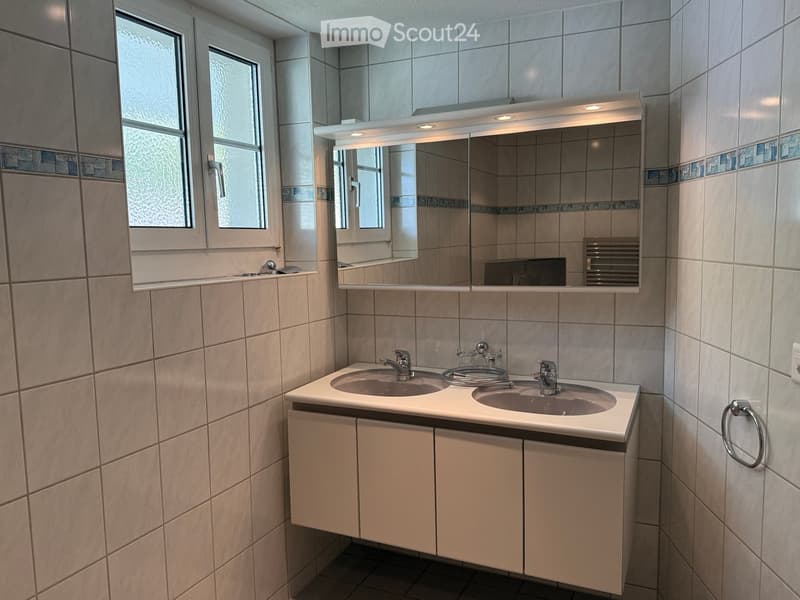 Modern bathroom with double sink, mirrored cabinet, and tiled walls.