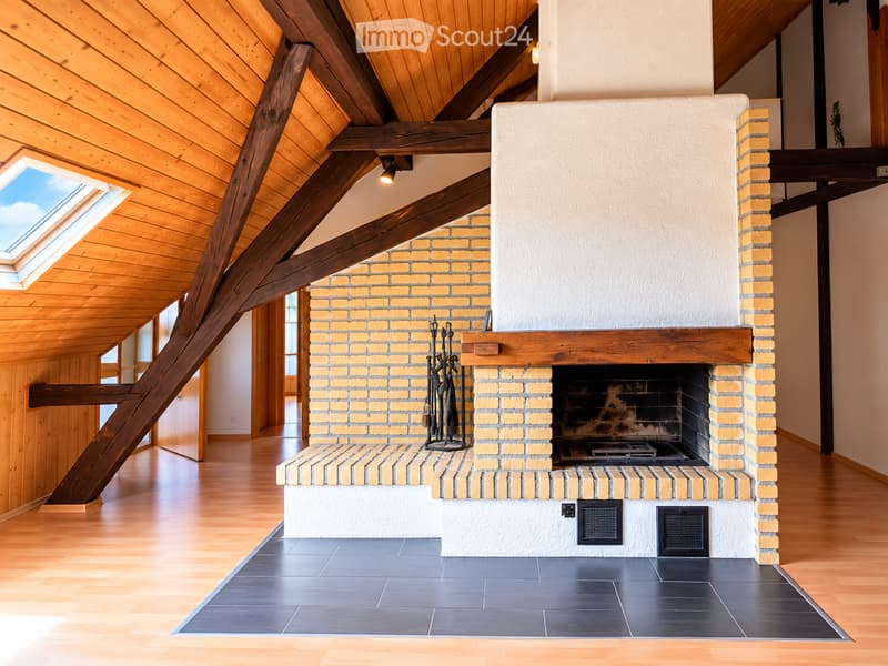 Modern living room with exposed wooden beams, skylight, and a brick fireplace with tools nearby.