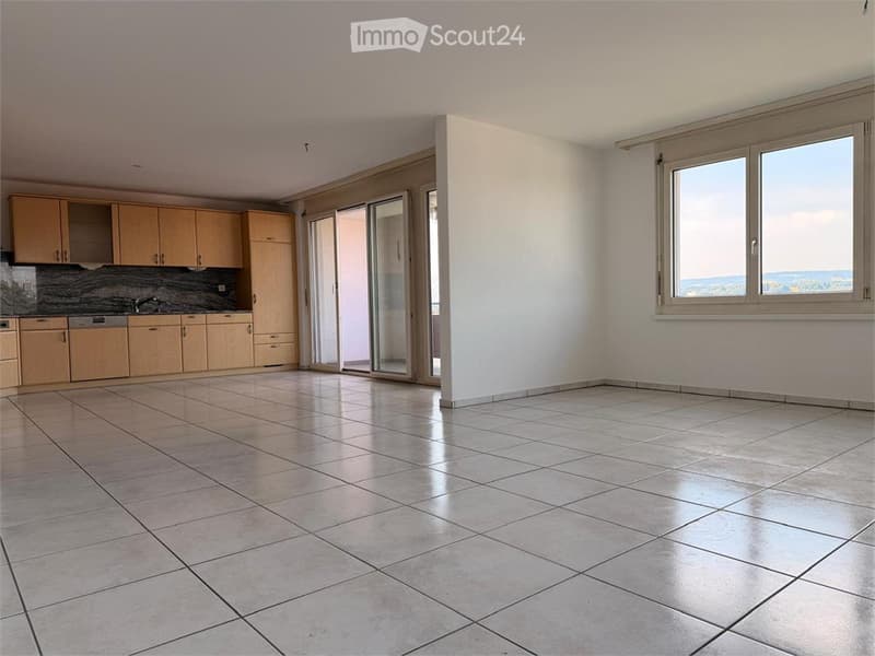 Bright, modern kitchen with light wooden cabinets, a tiled floor, and large windows offering a scenic view.
