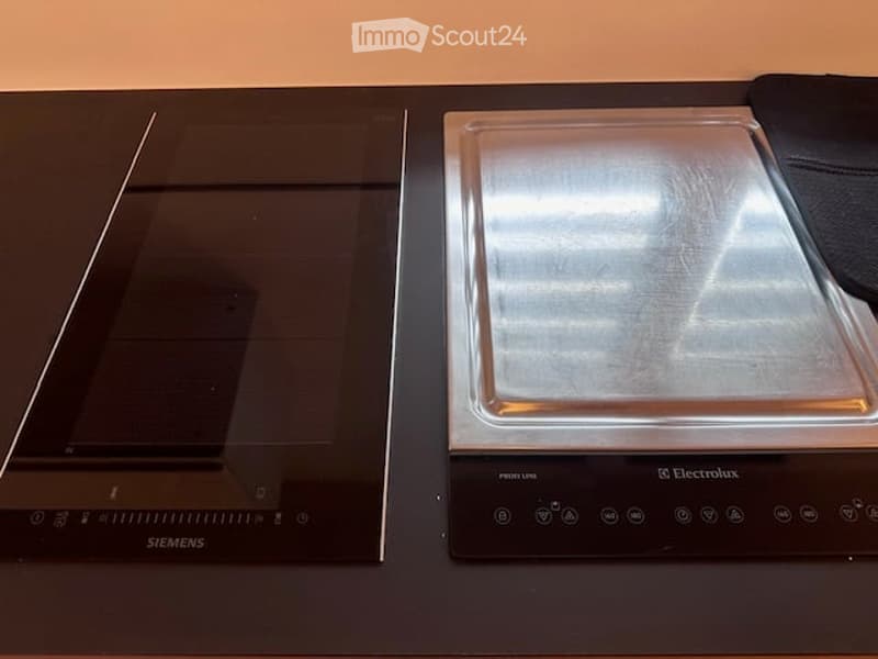 Modern kitchen featuring a sleek black Siemens induction cooktop and a stainless steel Electrolux electric induction hob.