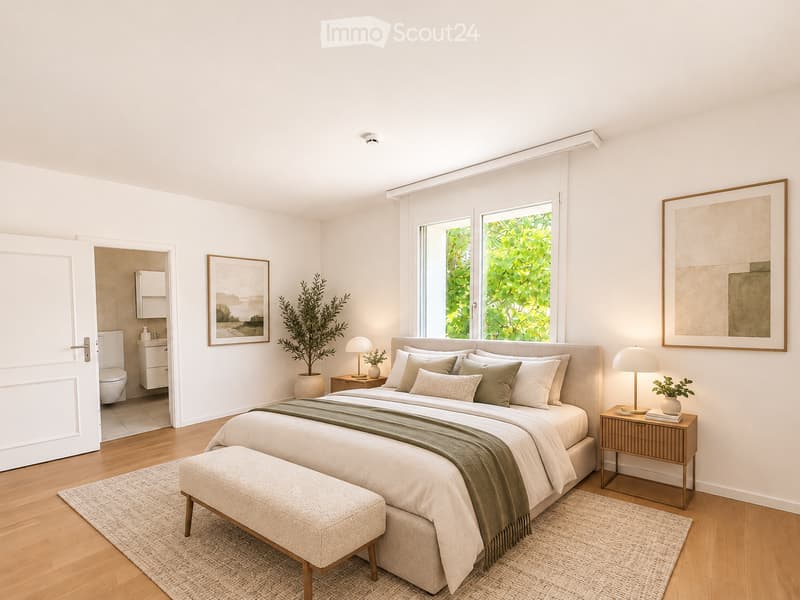 Modern, well-lit bedroom with a large bed, nightstands, lamps, a bench at the foot of the bed, and a small bathroom visible through an open door.