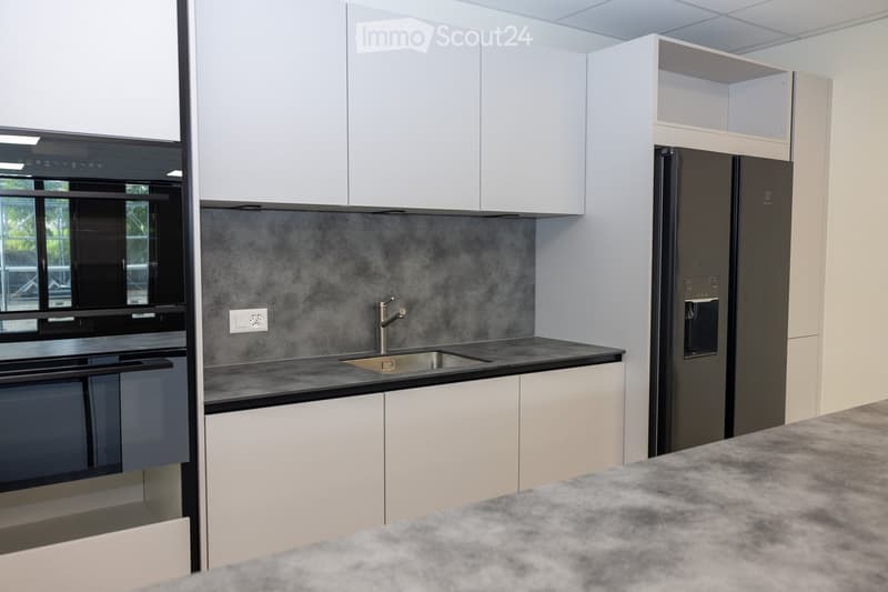 Modern kitchen with white cabinets, stainless steel appliances, and a grey backsplash.