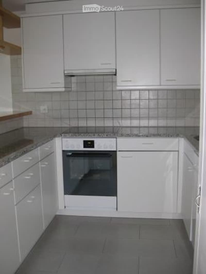 Modern kitchen with white cabinets, granite countertops, and a built-in oven.