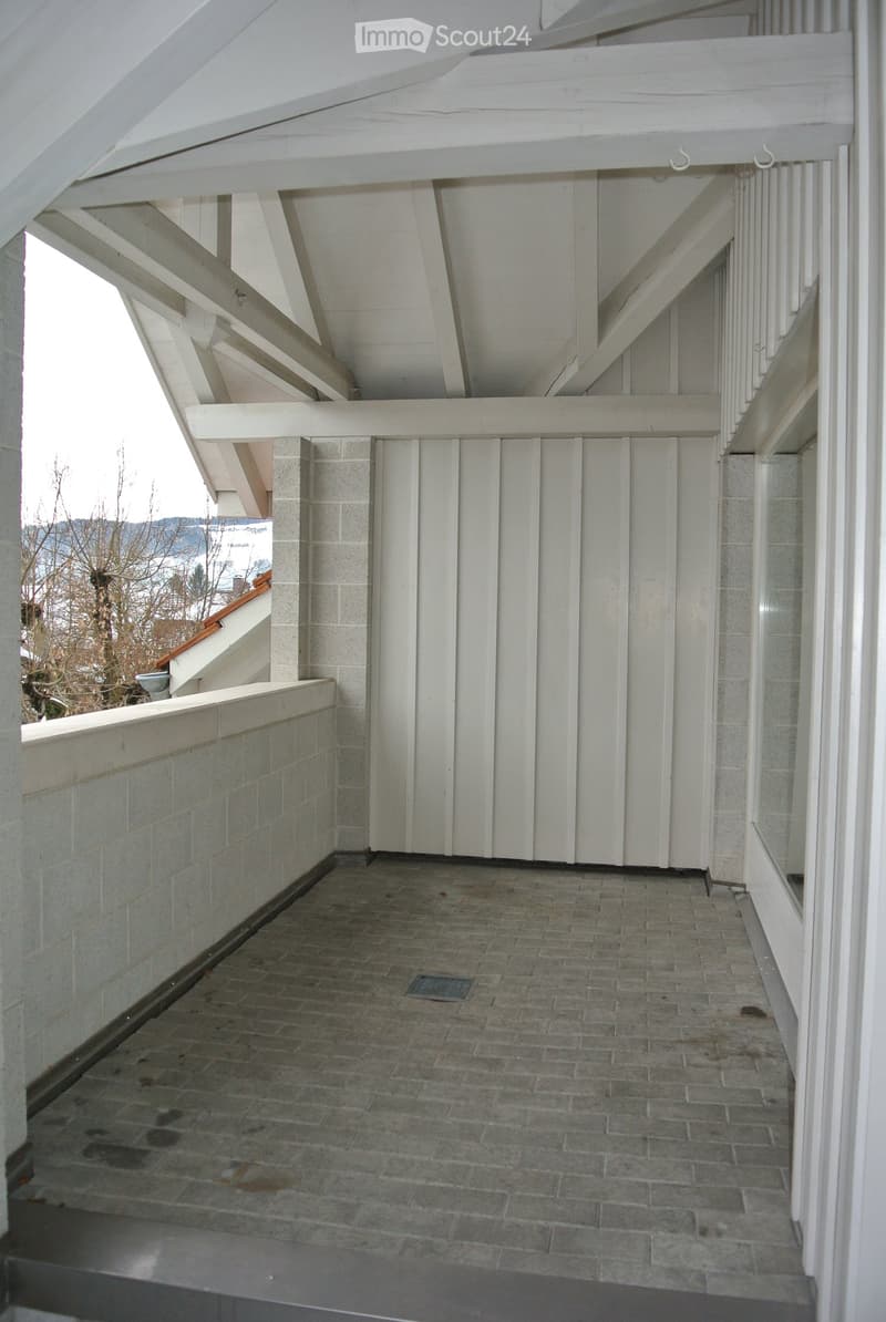 Balcony with brick flooring, white wooden railings, and a view of the surrounding area.