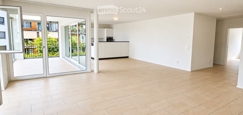 Empty living space with large sliding glass doors leading to a balcony, light-colored tiled flooring, and white walls.