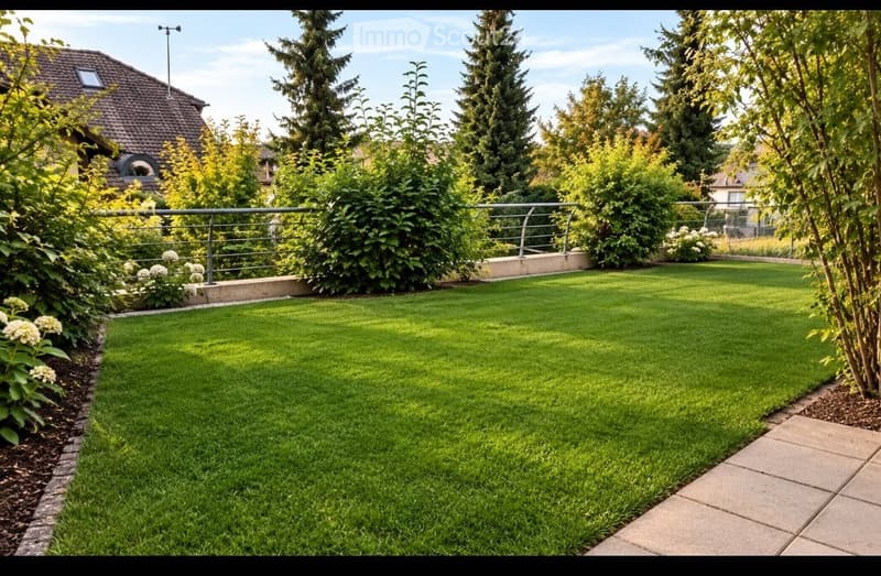 Well-maintained garden with a neatly trimmed lawn, surrounded by trees and shrubs, featuring a paved pathway and a metal railing along the edge.