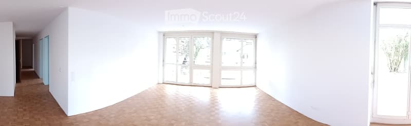 Empty room with white walls, wooden floor, large windows, and a sliding glass door leading outside.