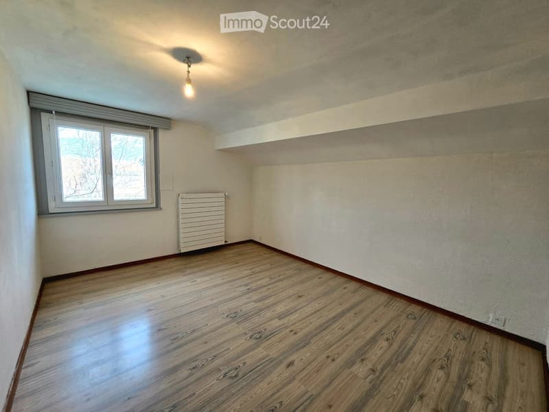 Empty room with wooden flooring, white walls, a window with blinds, and a radiator.