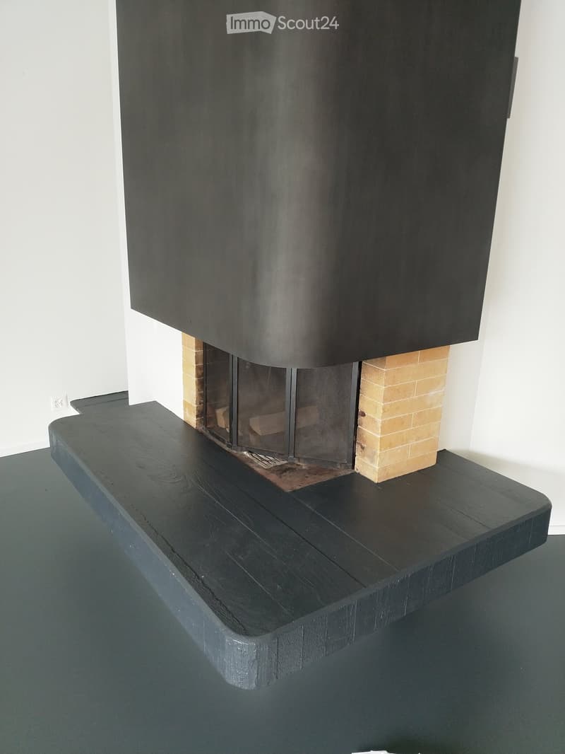 Modern fireplace with dark wooden mantel and beige brick accents, set against white walls.
