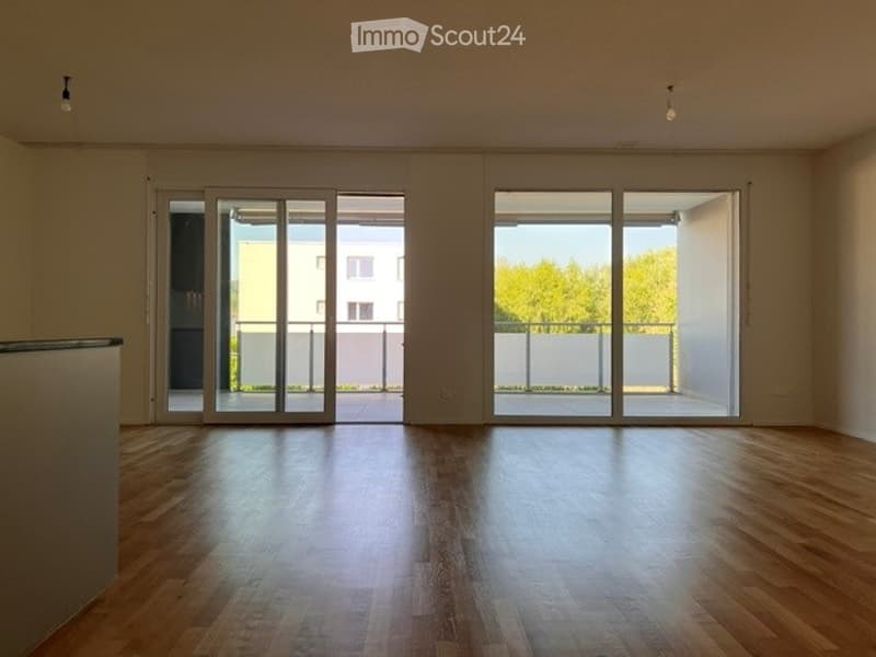 Empty room with wooden flooring and large glass sliding doors leading to a balcony area.