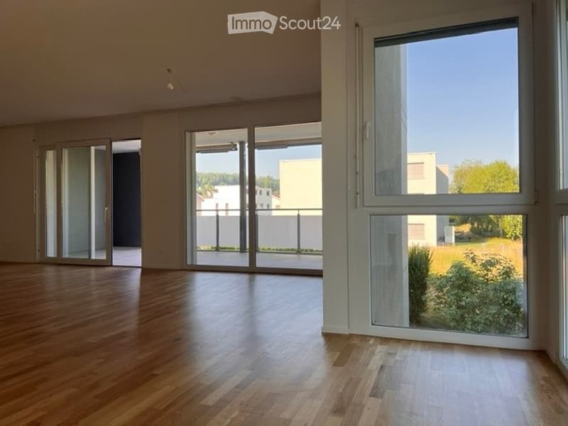 Empty room with wooden flooring, large glass sliding doors, and white walls.