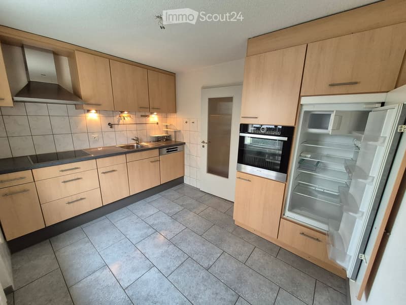 Modern kitchen with light wooden cabinets, stainless steel appliances, tiled backsplash, and granite tile flooring.