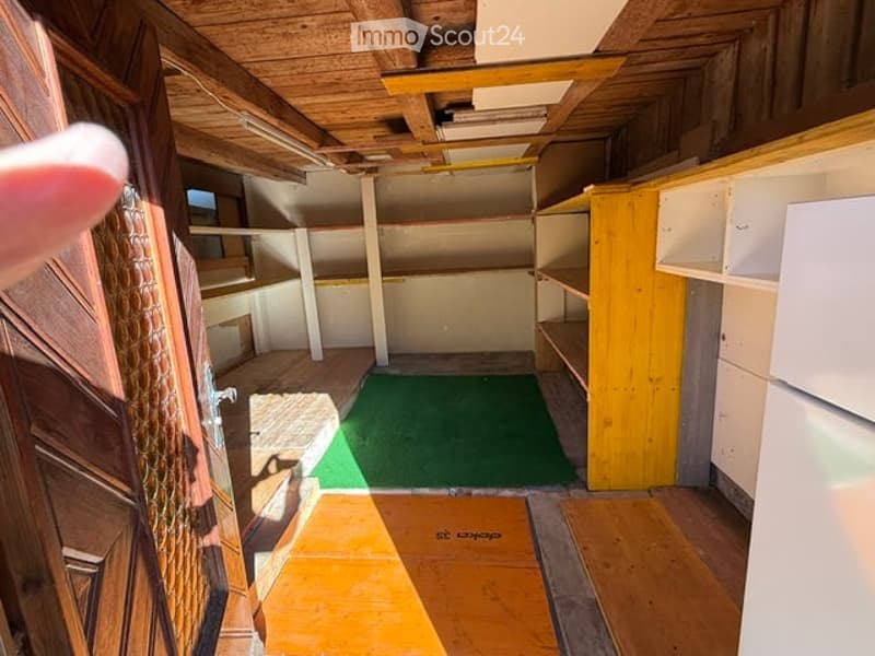 Empty room with wooden ceiling, green carpet, and built-in wooden shelves. No furniture or equipment present.