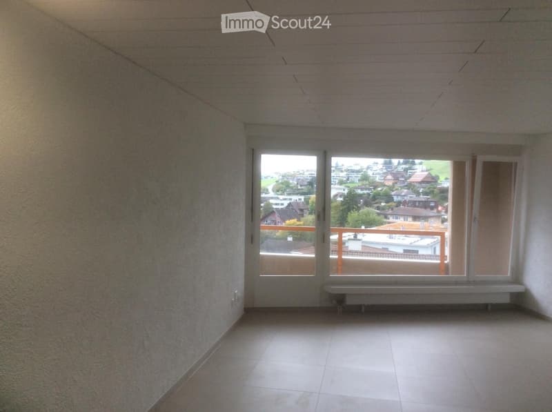 Empty room with tiled floor, large windows offering a view of the neighborhood, and a radiator beneath the windows.