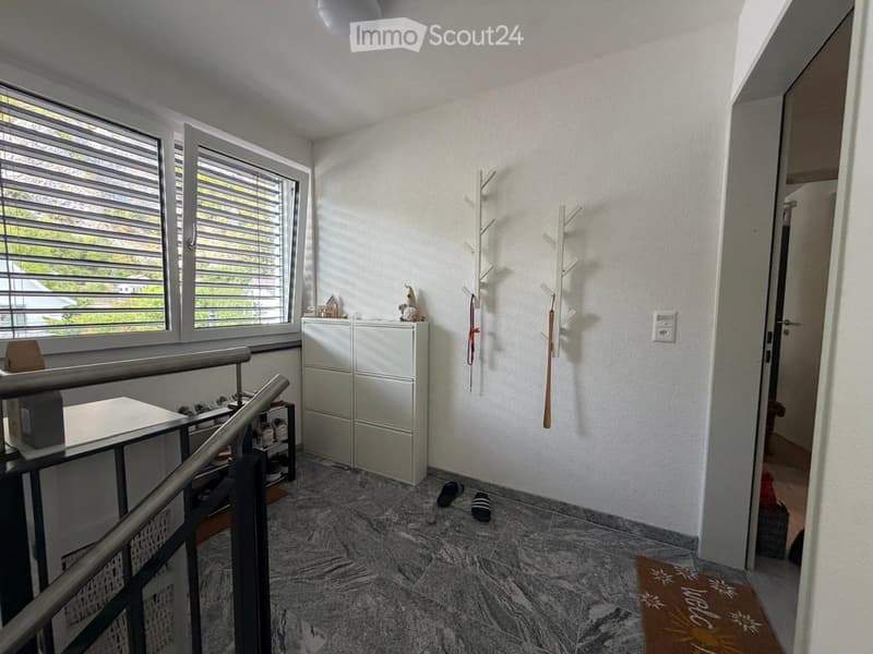 Hallway with marble flooring, white walls, coat rack, small table, cabinet, and a shelf with shoes.