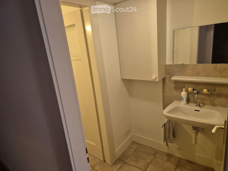 Small bathroom with a white sink, mirror, cabinet, and a towel hanging on the side.