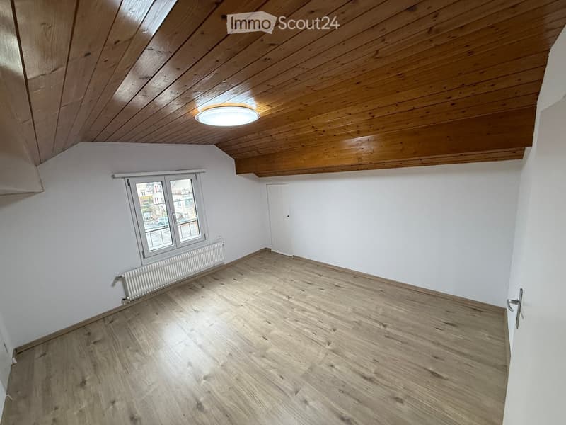 Empty room with wooden ceiling, white walls, wooden floor, window, radiator