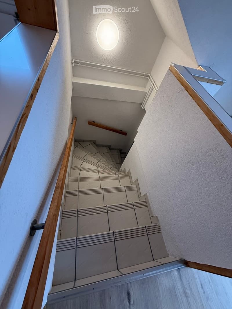 white tiled staircase with wooden handrails, white walls, circular ceiling light